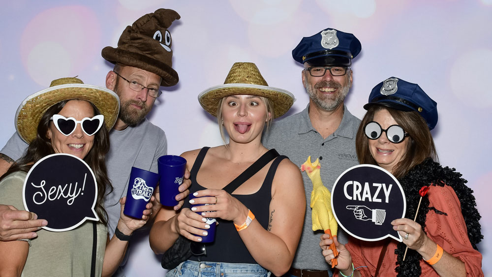 Adults having fun in the photo booth with props